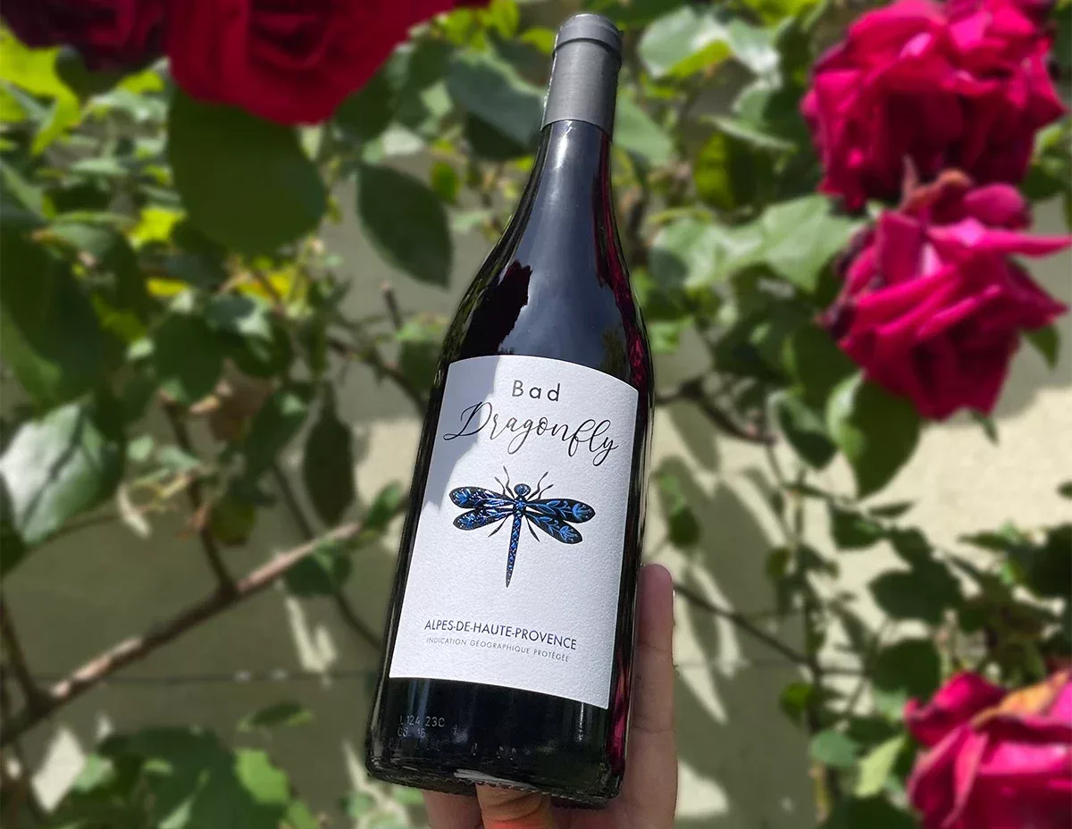 L’étiquette de la bouteille de vin, mise en scène dans un décor fleuri et naturel, a été conçue par Autajon Étiquettes Bourgogne.