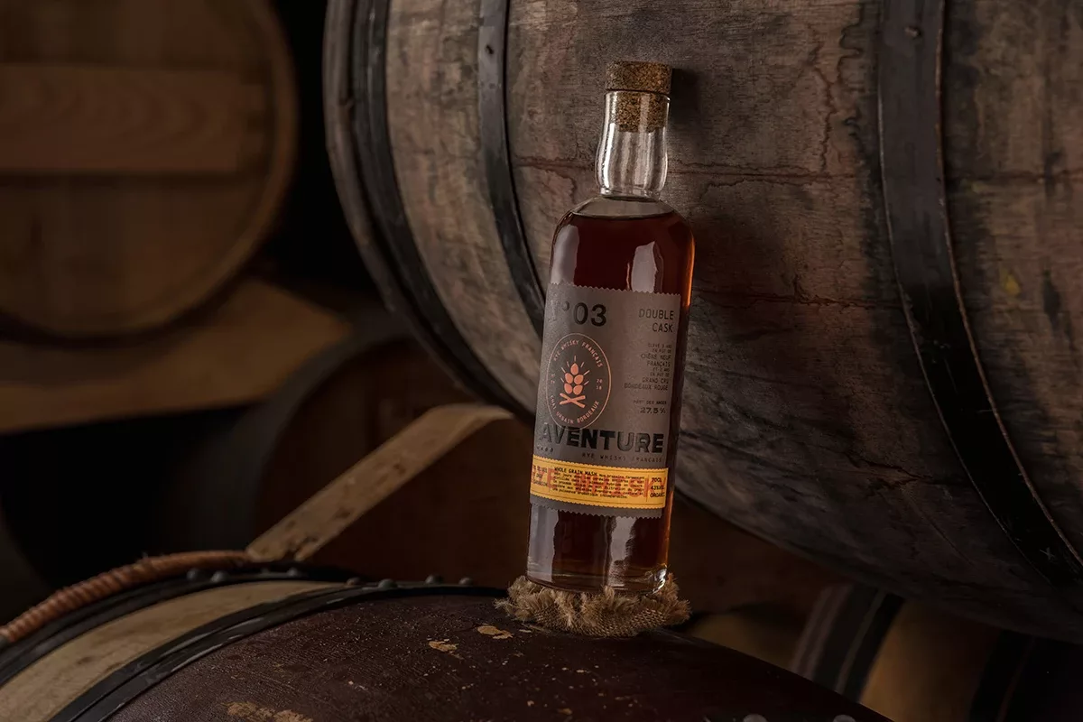 L’étiquette de la bouteille de whisky rye Aventure, présentée entre des tonneaux, a été réalisée par Autajon Étiquettes Atlantique