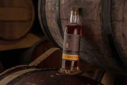 L’étiquette de la bouteille de whisky rye Aventure, présentée entre des tonneaux, a été réalisée par Autajon Étiquettes Atlantique
