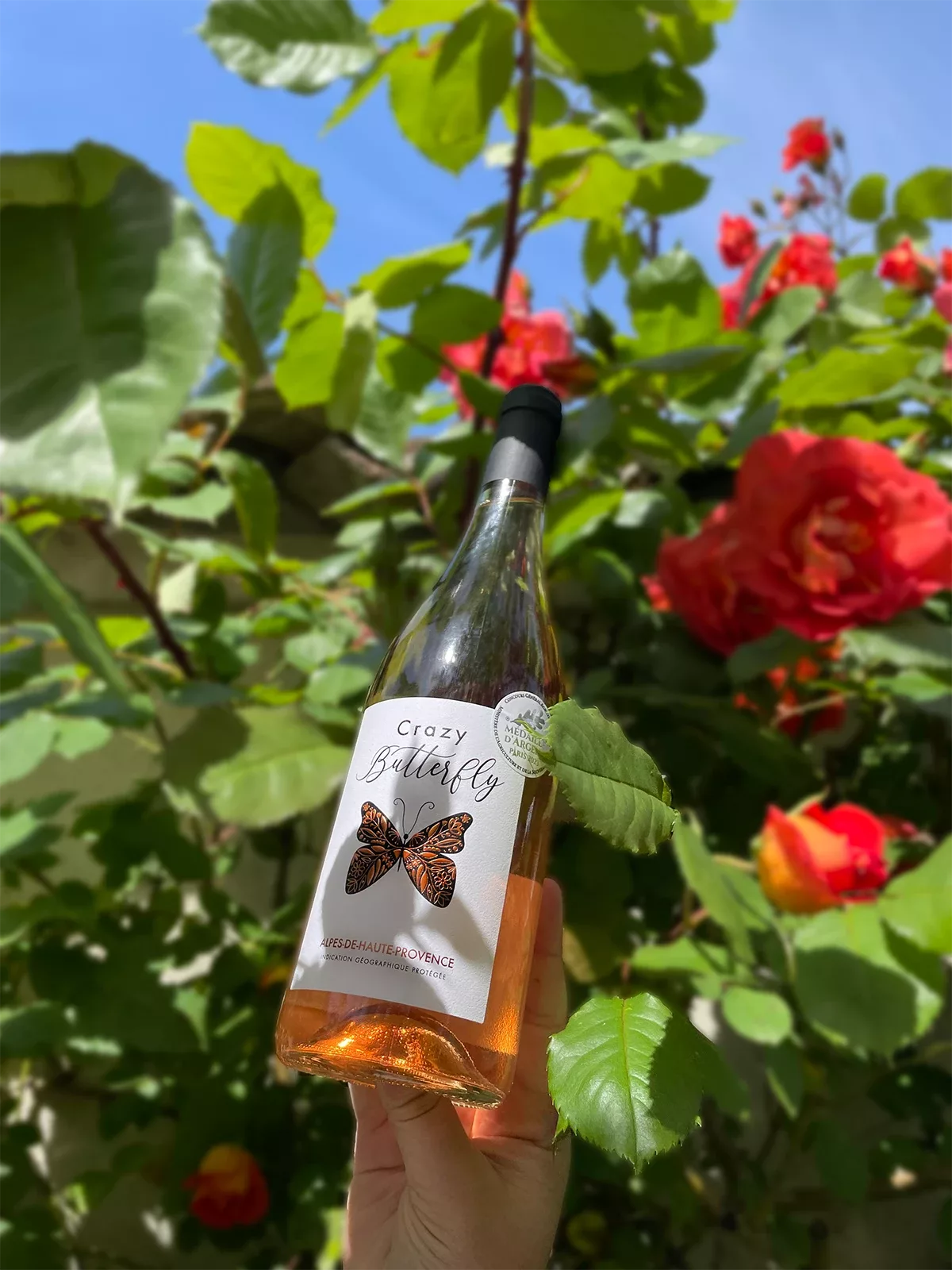 L’étiquette de la bouteille de vin rosé, mise en scène dans un décor fleuri et naturel, a été conçue par Autajon Étiquettes Bourgogne.