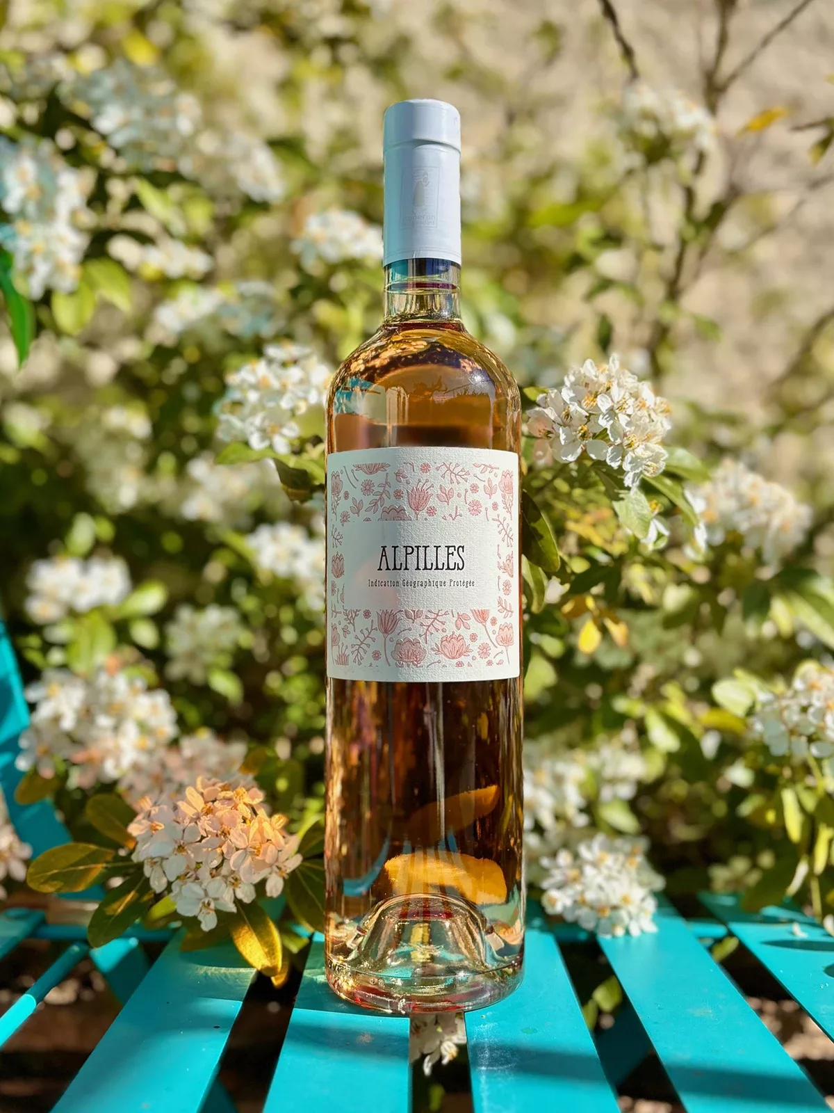 L’étiquette de la bouteille de vin, mise en scène dans un décor fleuri et naturel, a été conçue par Autajon Étiquettes Bourgogne.