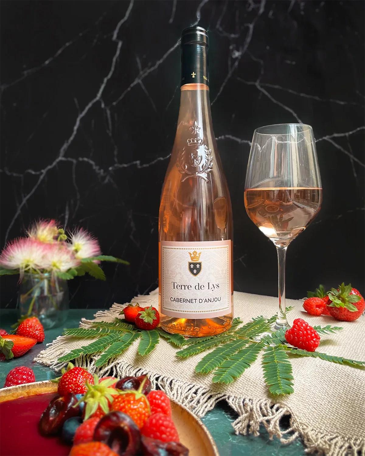 L’étiquette de la bouteille de vin rosé, présentée sur une table fruitée, a été réalisée par Autajon Étiquettes Bourgogne