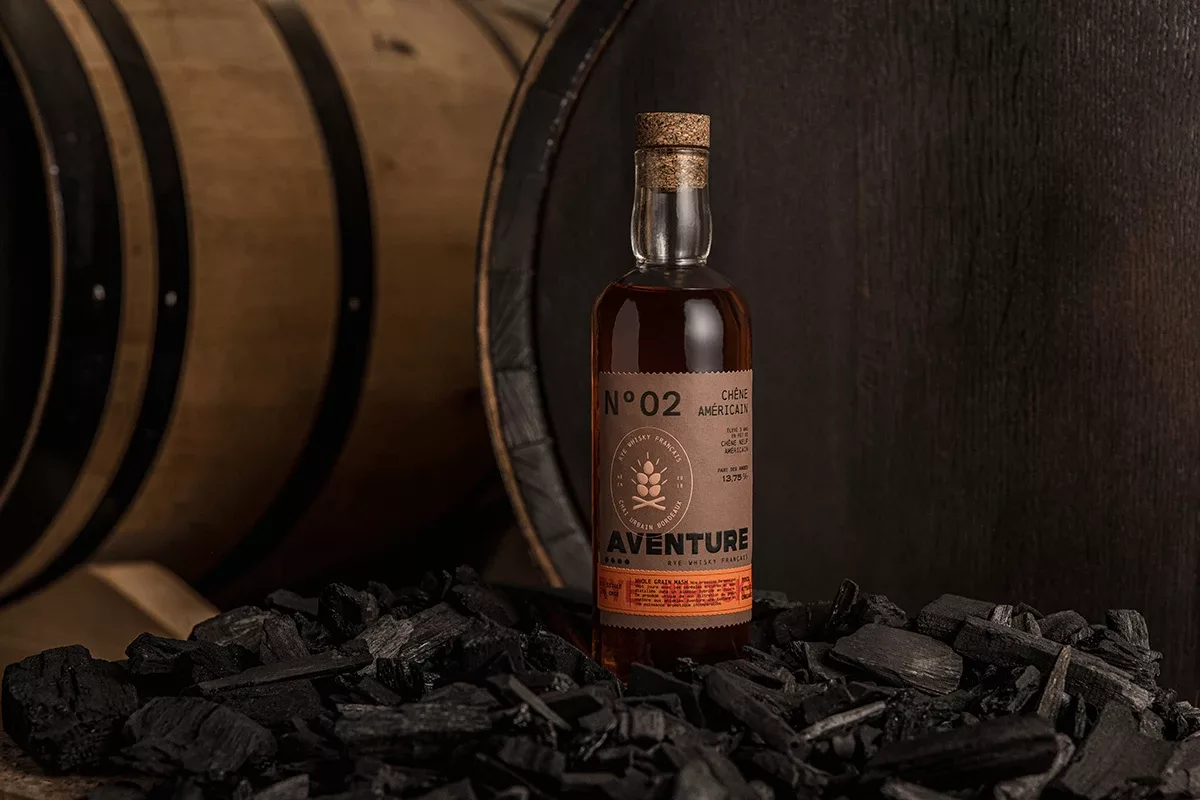 L’étiquette de la bouteille de whisky rye Aventure, présentée sur un tas de charbon, a été réalisée par Autajon Étiquettes Atlantique